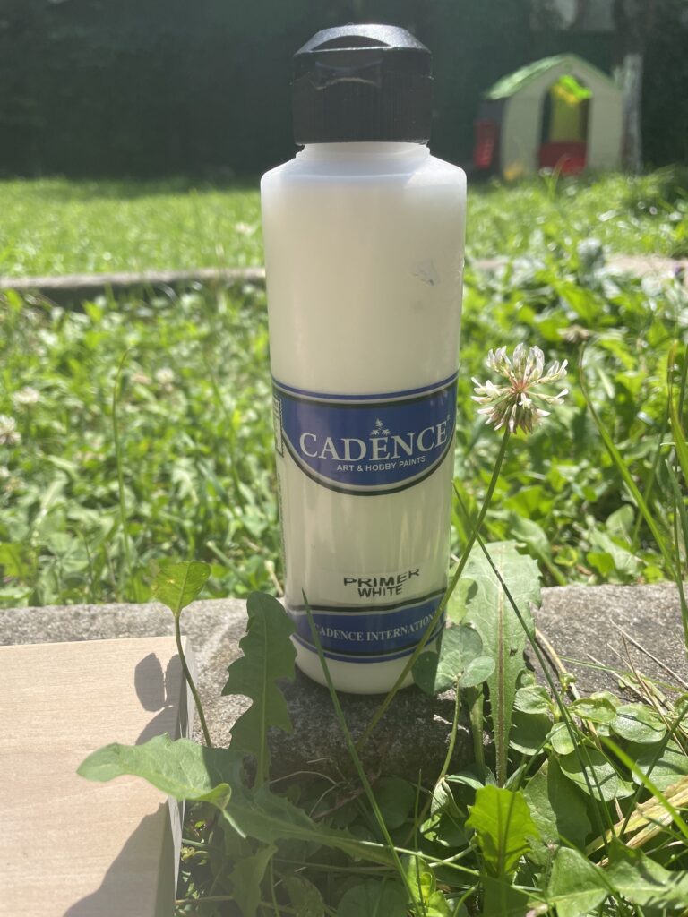 a bottle of gesso resting on the grass on a sunny day